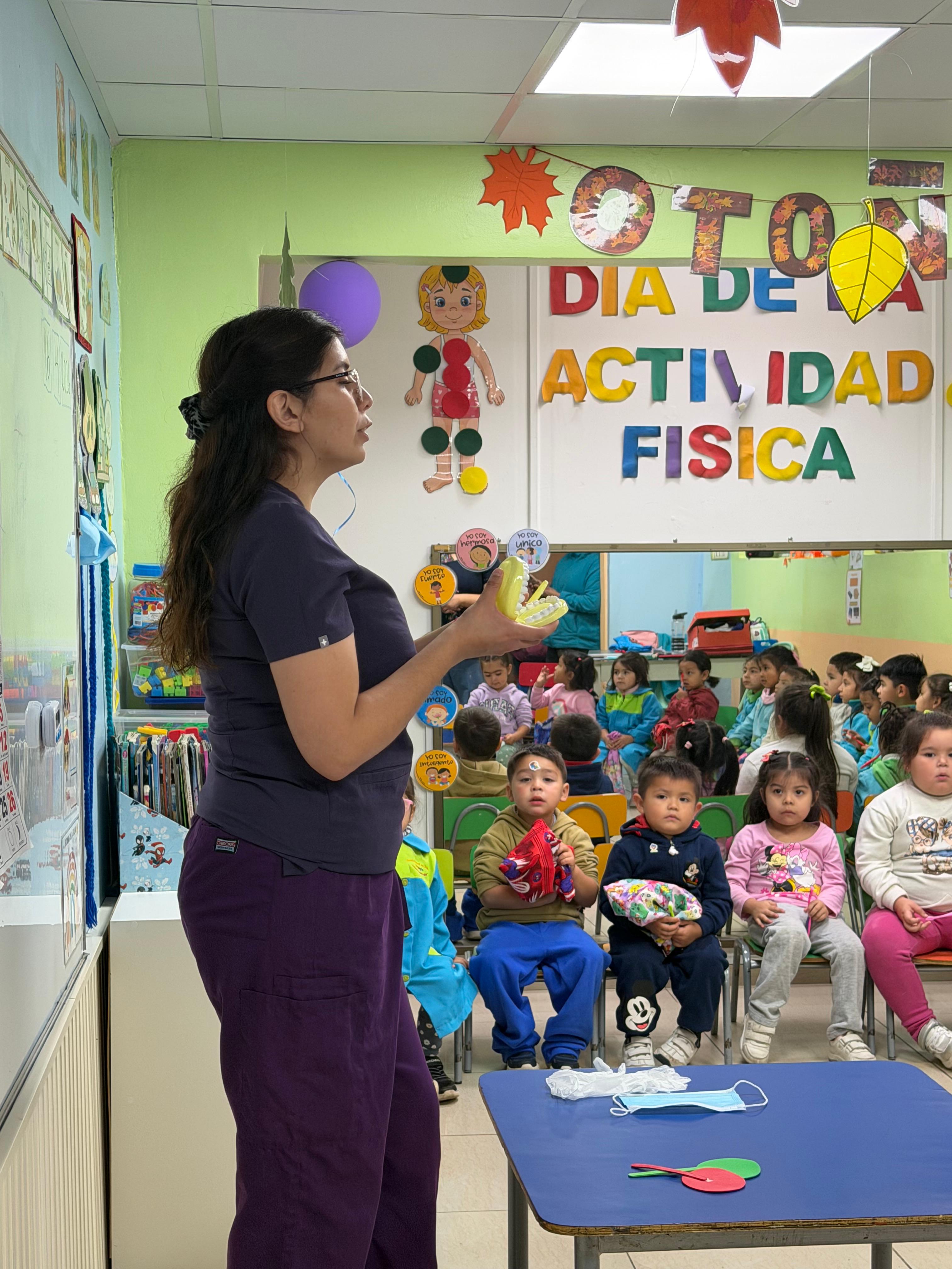 Profesional de la escuela mostrando un modelo dental a los niños durante una charla de salud