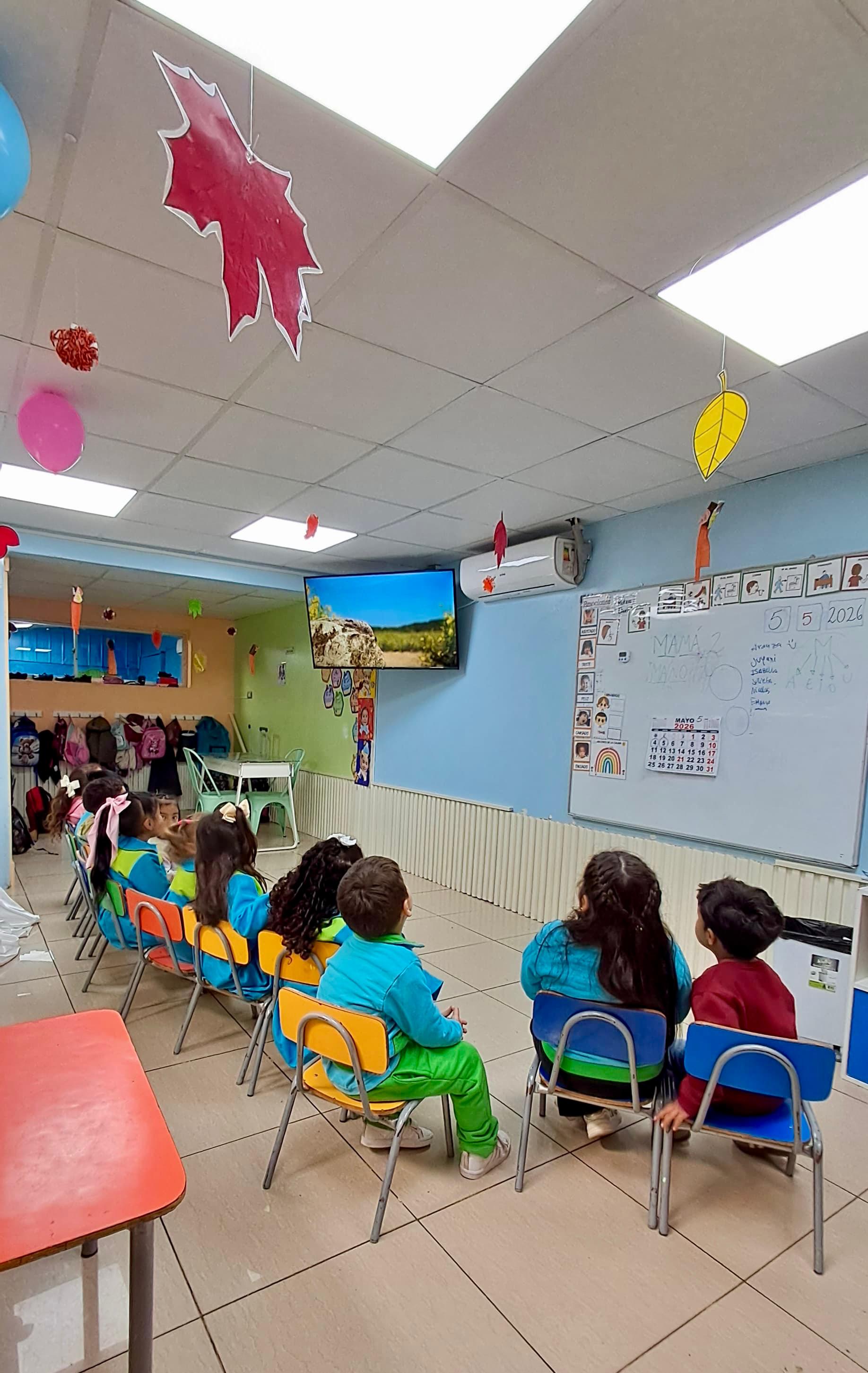 Niños sentados atentos viendo un video educativo en la sala de clases